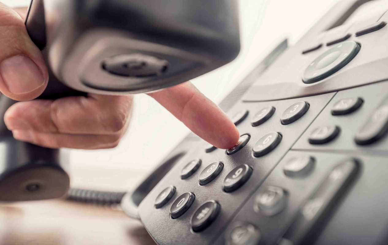 Close up of a man dialling a number on a black telephone